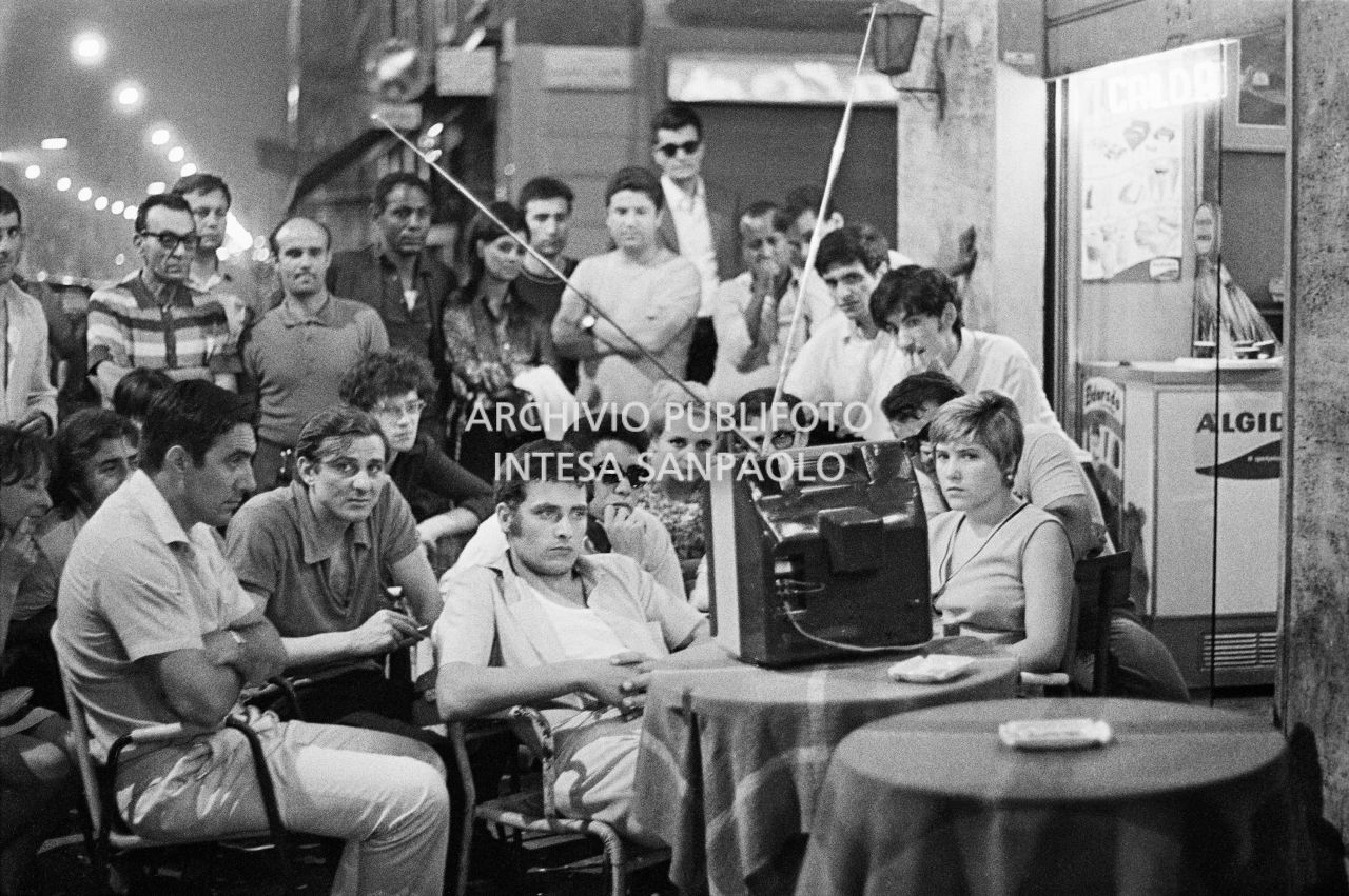A group of people follow the live transmission of the Apollo 11 moon landing