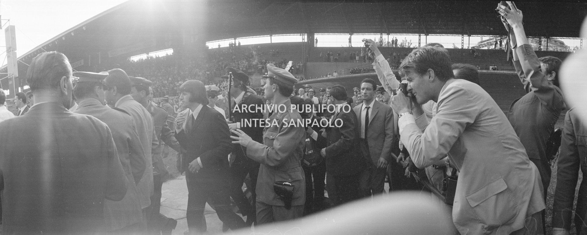 I Beatles, scortati dalle forze dell'ordine, fanno il loro ingresso al Vigorelli di Milano
