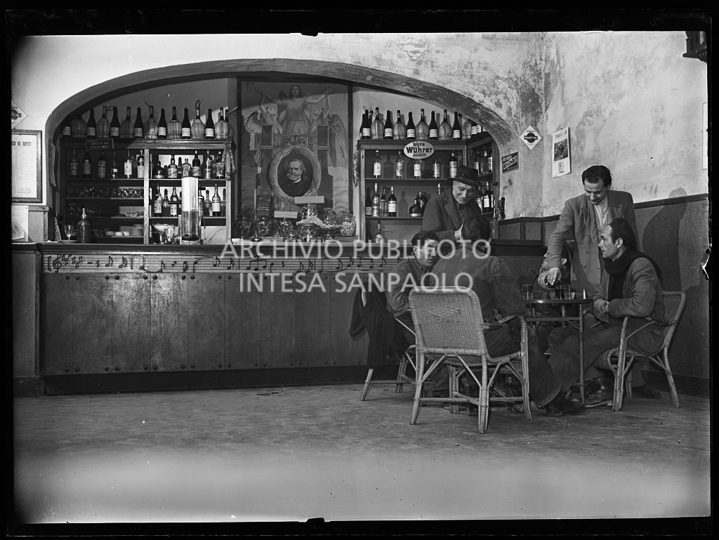 Avventori al tavolo di un bar a Parma con decorazioni che omaggiano  Giuseppe Verdi