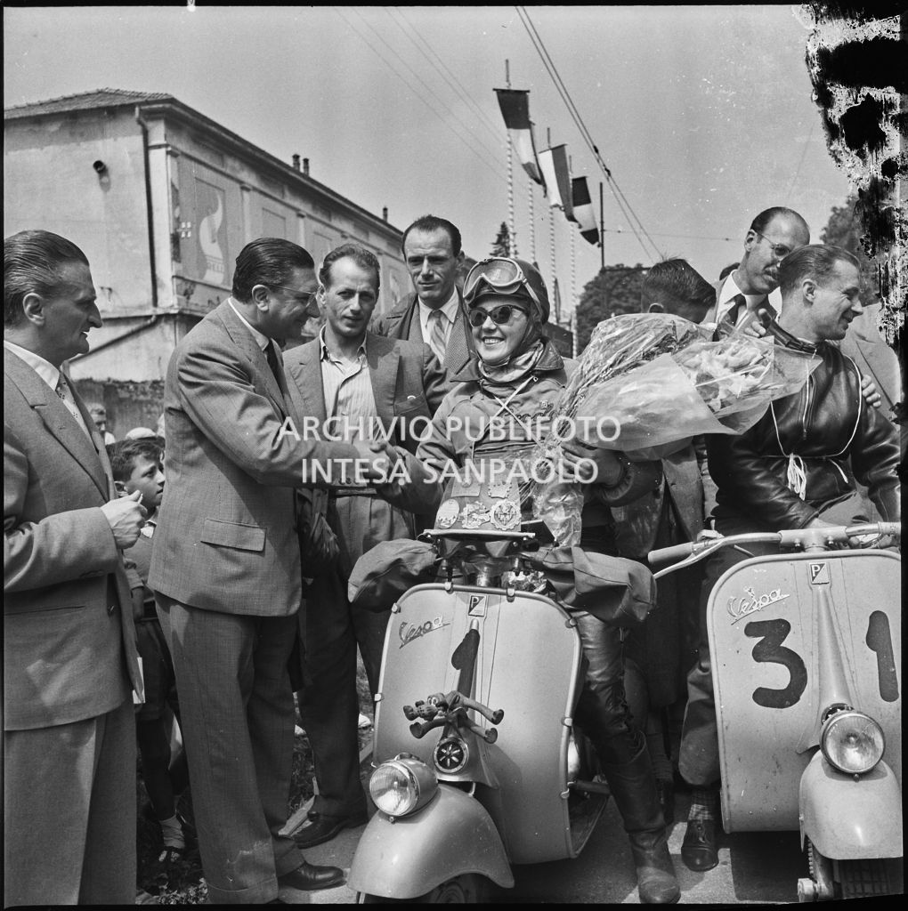 Ada Pace, del Vespa Club Torino (numero di gara 1), in sella alla sua Vespa riceve un mazzo di fiori durante l'Audax Vespistico 1000km, accanto a lei Mario Minini del vespa Club Brescia con numero di gara 31.