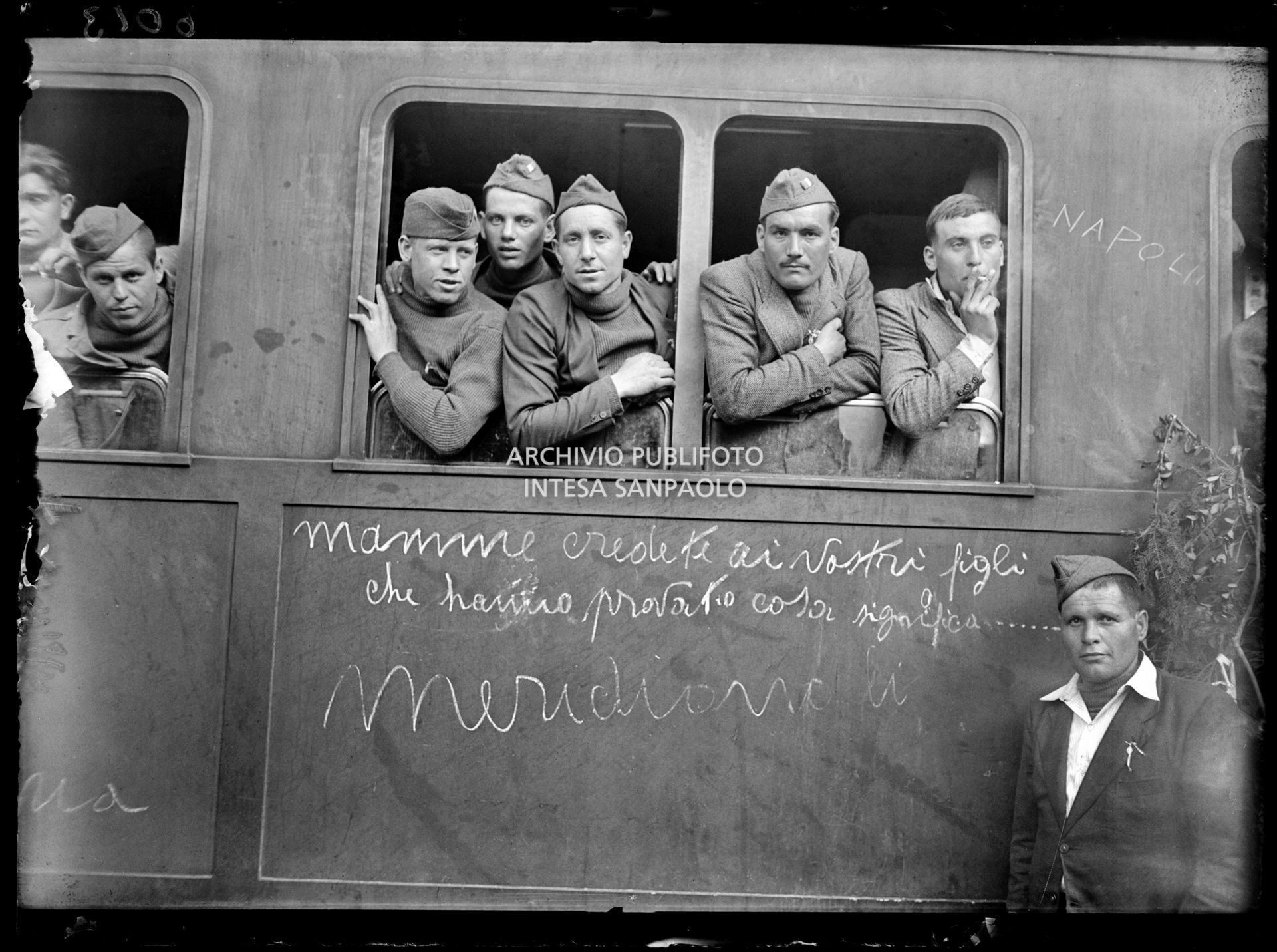 Un gruppo di reduci dalla prigionia in Russia si affaccia da un finestrino di un treno della Pontificia Commissione di Assistenza durante in sosta alla Stazione Centrale di Milano; sul convoglio è visibile la scritta "Napoli", "Mamme credete ai vostri figli che hanno provato cosa significa....meridionali"