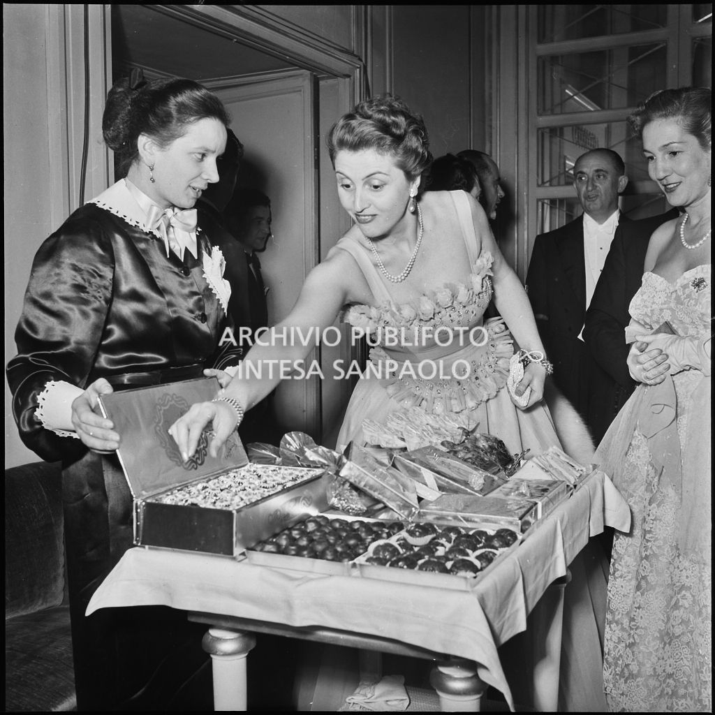 Le signore Castiglia e Morini al banchetto dei cioccolatini, al Teatro alla Scala, in occasione della serata inaugurale della stagione lirica 1951-1952 con l'opera "I vespri siciliani" di Giuseppe Verdi, diretta da Victor de Sabata, con la regia di Herbert Graf