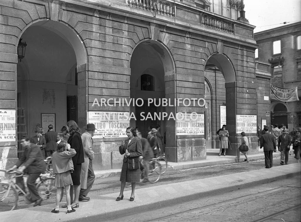 Esterno del Teatro alla Scala con affissi, sulle colonne della galleria delle carrozze, i manifesti del concerto di riapertura del Teatro, ricostruito dopo la guerra, diretto da Arturo Toscanini