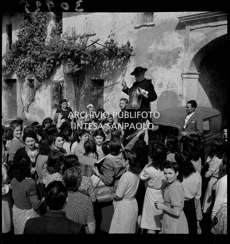 Don Balduzzi, standing on a car, hands out leaflets with the picture of Jesus to the rice-weeders near Vigevano