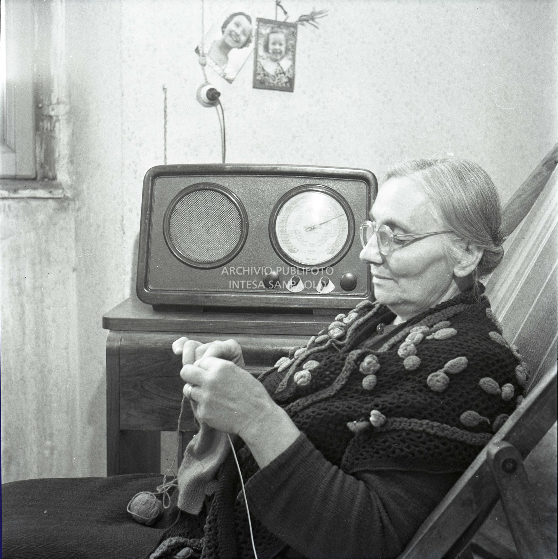 An old woman knits while listening to the radio
