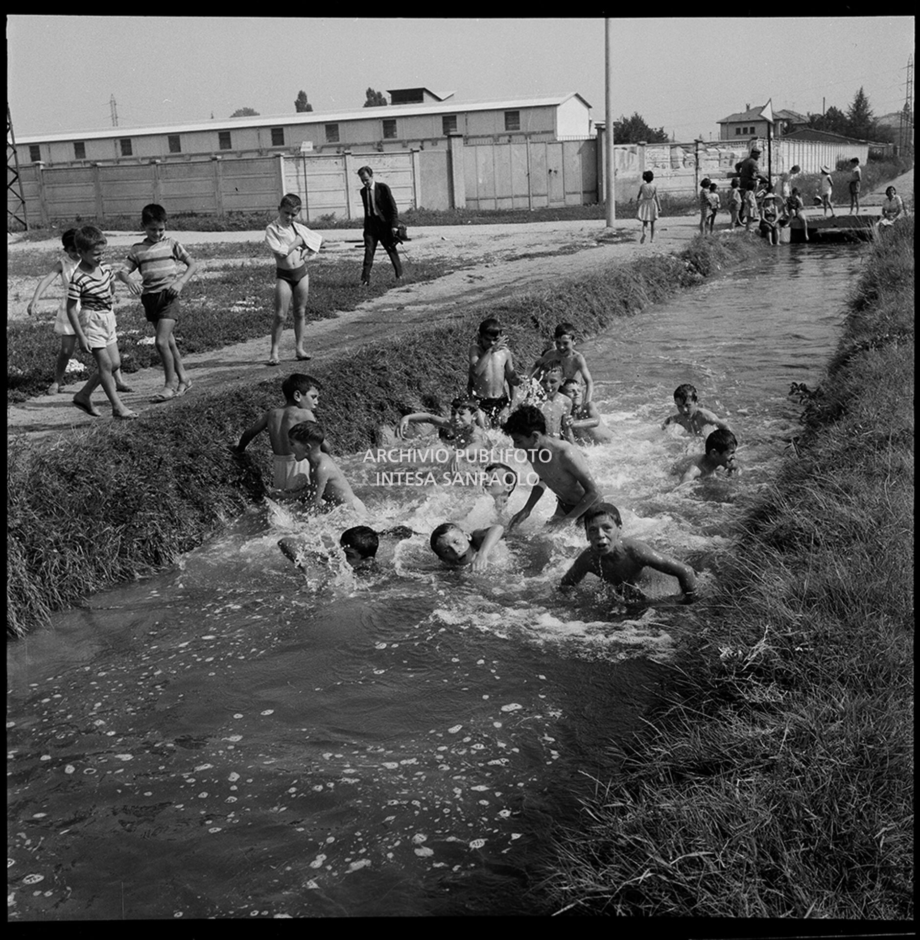 Bambini fanno il bagno in un canale alla periferia di Milano
