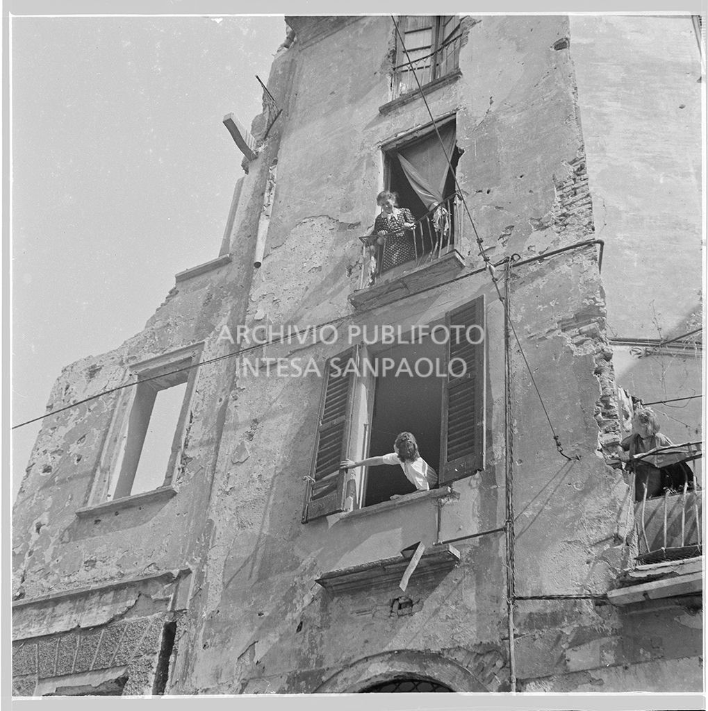 Women chatting in front of bomb-shelled houses in Milan