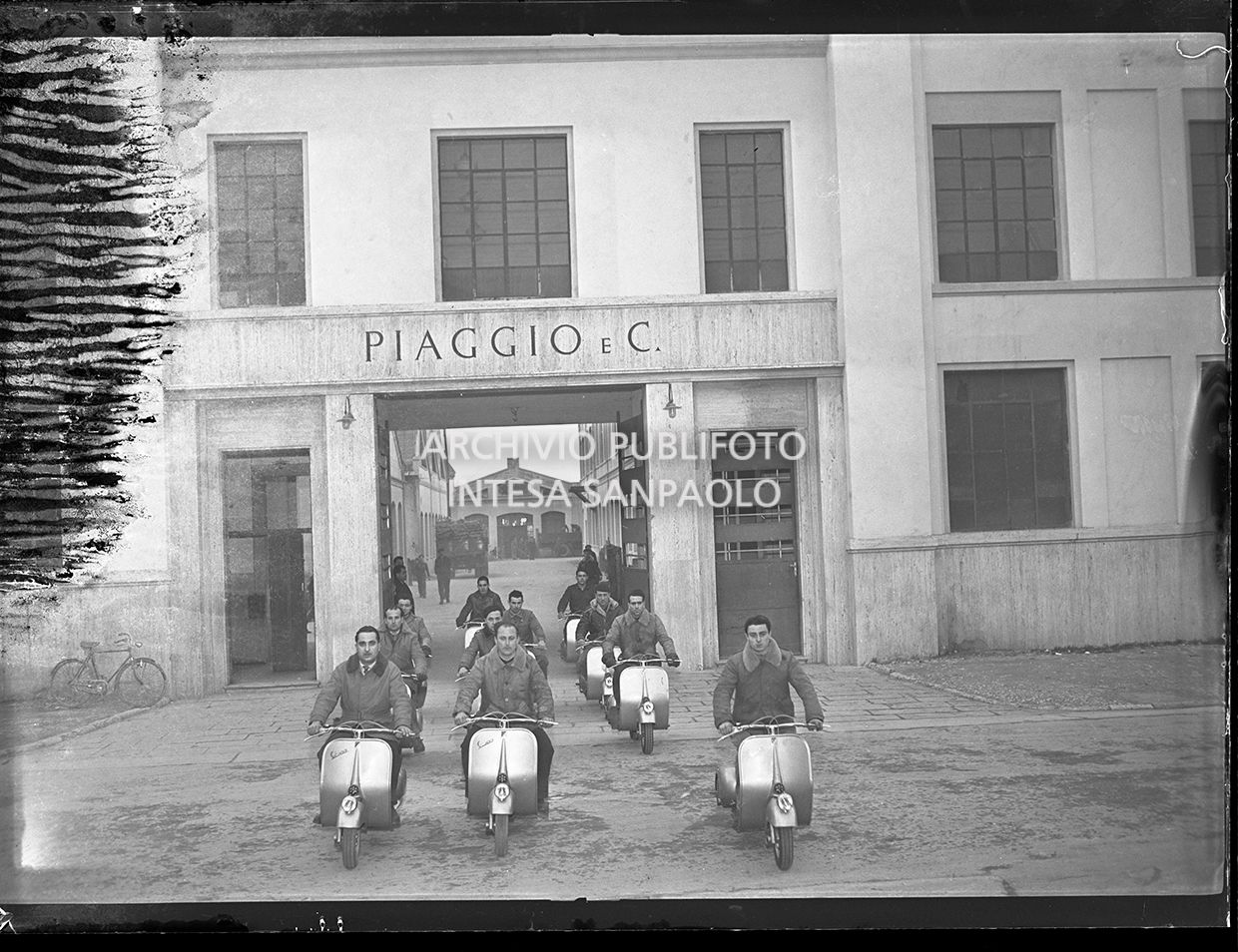 Workers from the Piaggio factory driving Vespa in front of the gates to the Pontedera plant