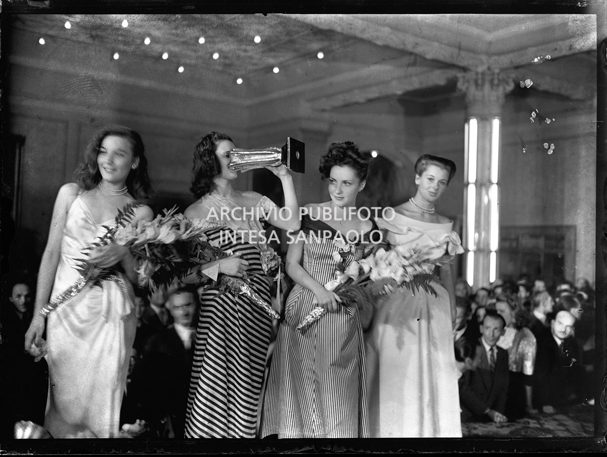 Lucia Bosè, Miss Italia 1947, drinks from the trophy cup she has just won, surrounded by other competitors: from left, Gianna Maria Canale, Gina Lollobrigida and Eleonora Rossi Drago, in Stresa