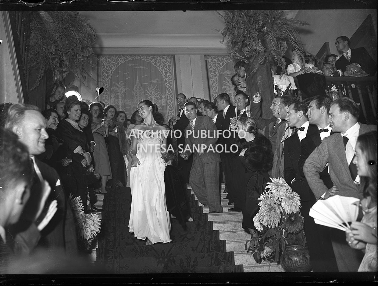 Mariella Giampieri, Miss Italia 1949, comes down the stairway flanked by two rows of admirers