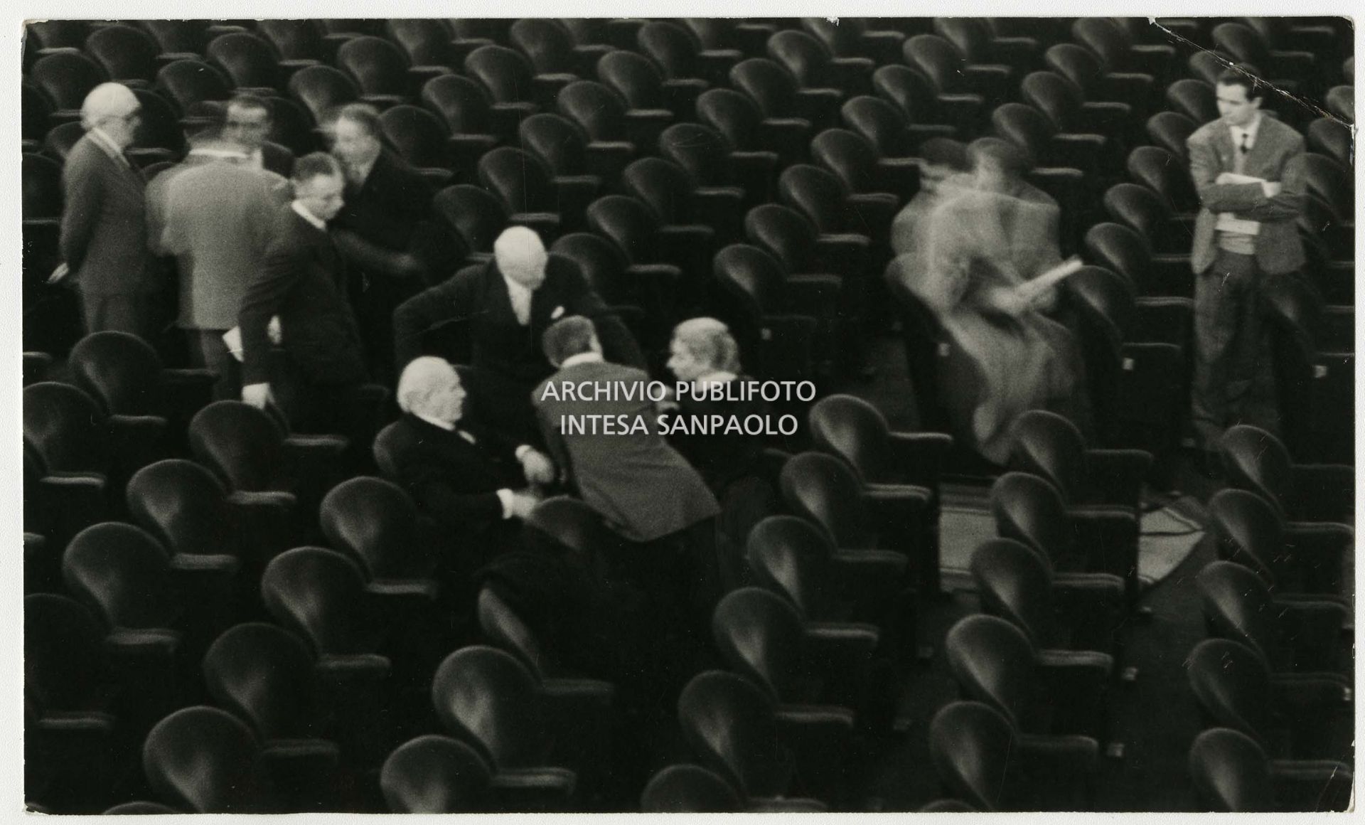 Original caption by Publifoto Agency on the back of the print:
								"And everyone felt really small.
								A historical photo. Milan, 1 December 1954. 
								This historic photograph shows Maria Callas with three great conductors: Arturo Toscanini, Victor De Sabata and Antonino Votto. The photograph was taken on 1 December 1954, when Toscanini wanted to attend one of the last rehearsals of La Vestale that would open the Milan opera season on the 7th of December that year. The maestro lingered in the stalls for a long time and then wanted to talk to Callas. As can be clearly seen in photo 237189 (Antonino Votto from behind), all three conductors are looking towards Callas who is talking about her interpretation of Spontini's opera. Maria Callas' last meeting with Toscanini was in 1955, during rehearsals for Carmen."