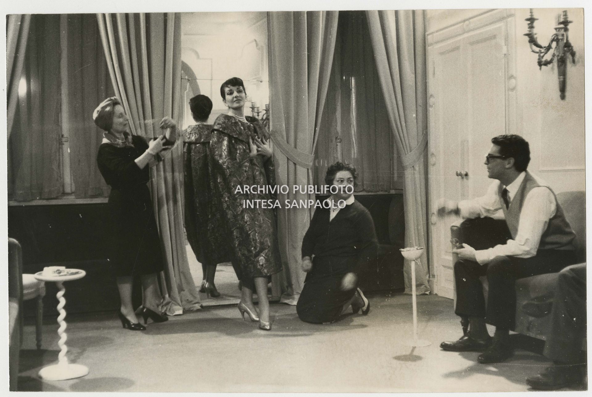 Maria Callas in the Biki atelier tries on an overcoat assisted by fashion designer Elvira Leonardi Bouyeure, known as Biki, and a seamstress