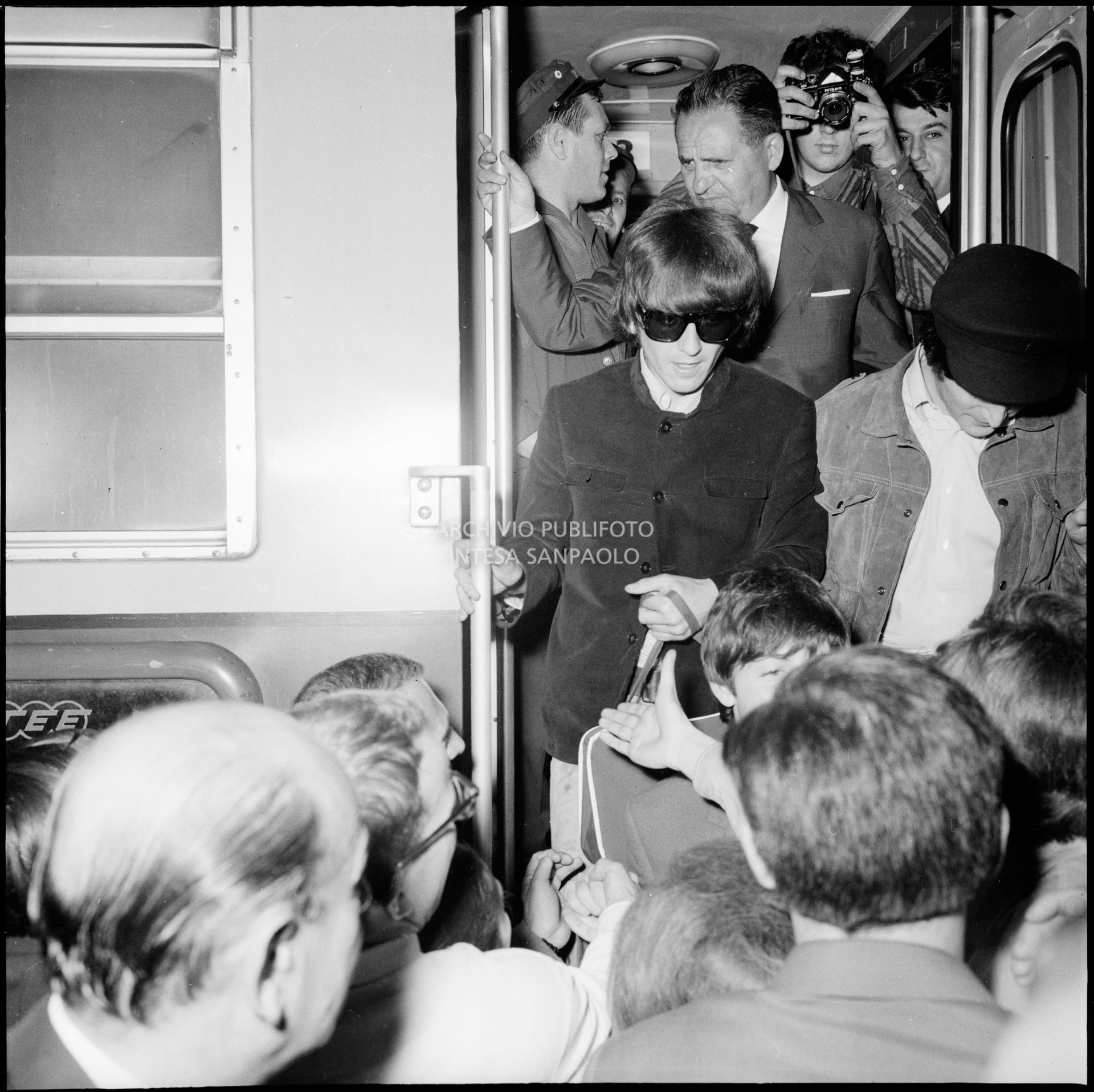 George Harrison, John Lennon e Paul McCartney scendono dal treno alla Stazione Centrale di Milano