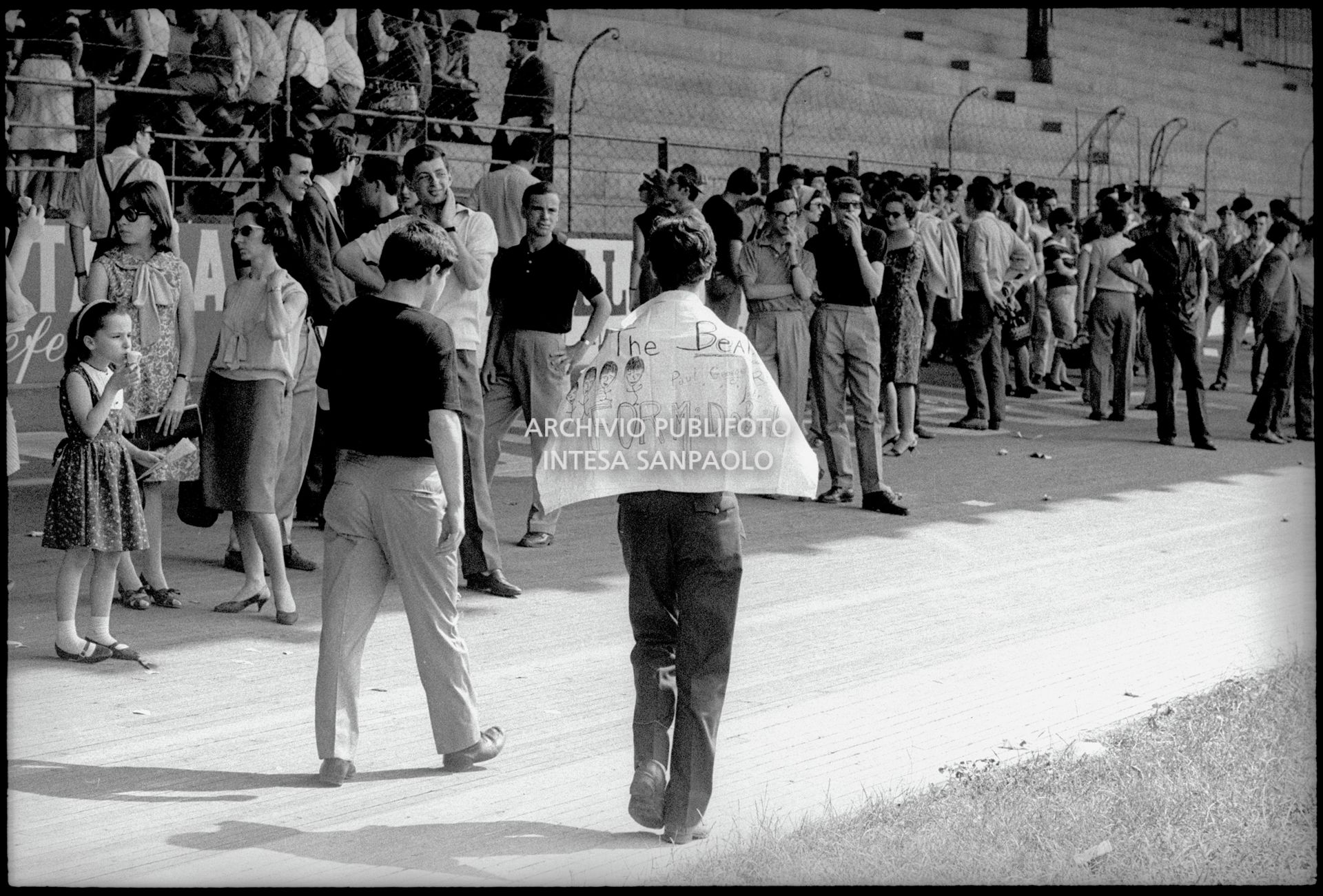 Pubblico cerca riparo all'ombra in attesa dell'inizio del concerto pomeridiano dei Beatles al Vigorelli di Milano