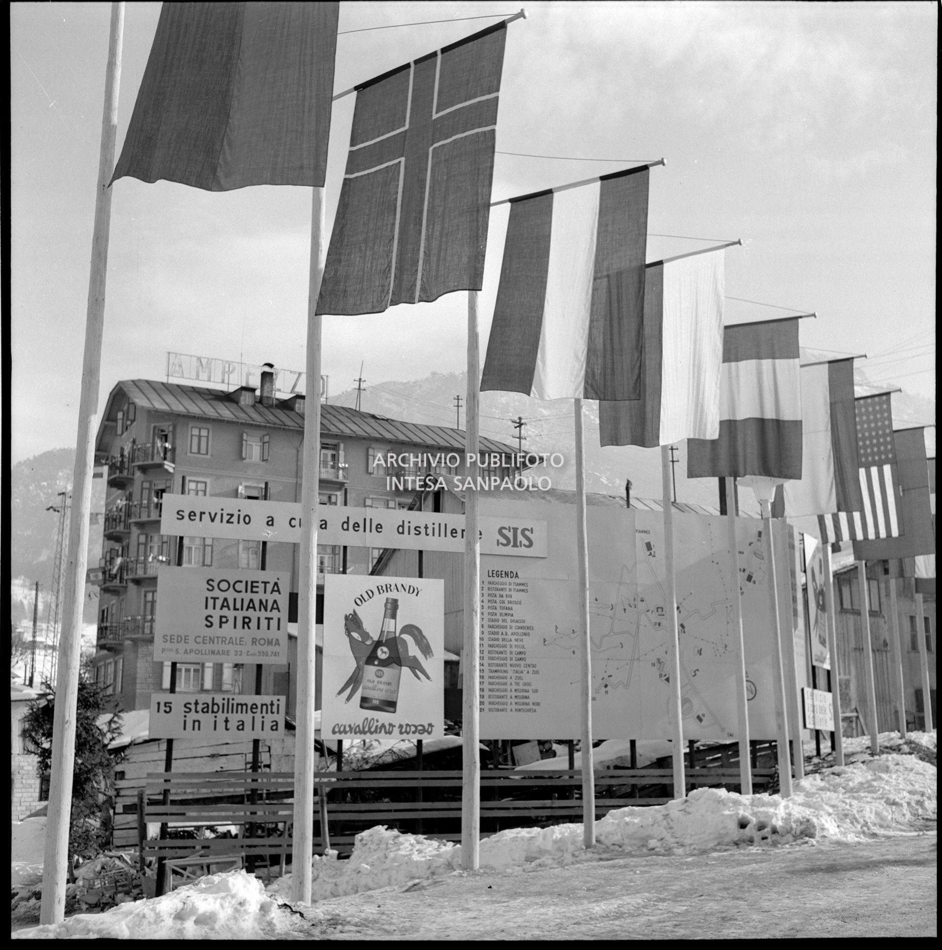 Società Italiana Spiriti billboards, including one for Old Brandy Cavallino Rosso, displayed under the various national flags during the 7th Winter Olympic Games
