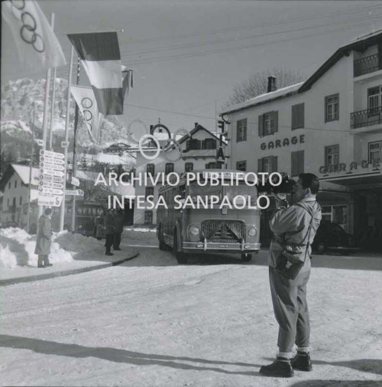 A member of RAI staff and a bus to take staff working for the 7th Winter Olympic Games, in a street in Cortina d'Ampezzo