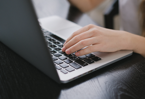 Image of hand typing at computer